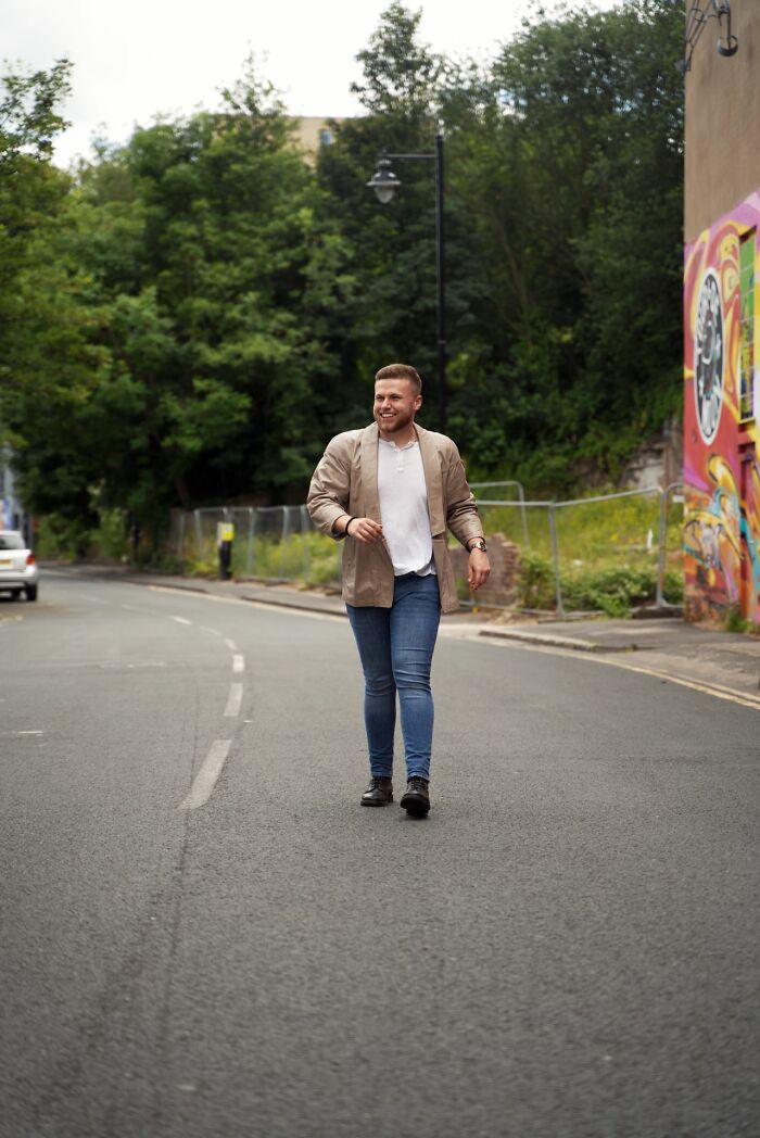 A man walks down a street next to a colorful graffiti wall and trees, reflecting the cultural context of 'white phrases'.