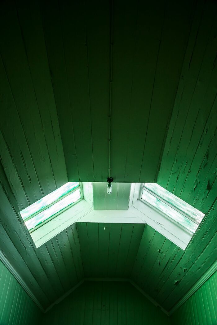 A green wooden attic room with a single light bulb and two windows, representing unusual ways people have lost their lives.