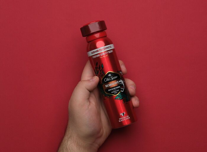 Hand holding a red Old Spice deodorant spray can, an item that swapped audiences.