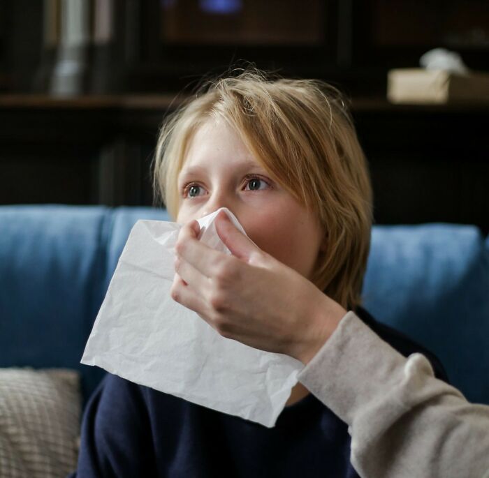 A child with blonde hair getting their nose wiped with a tissue, symbolizing vulnerability in public horror stories.