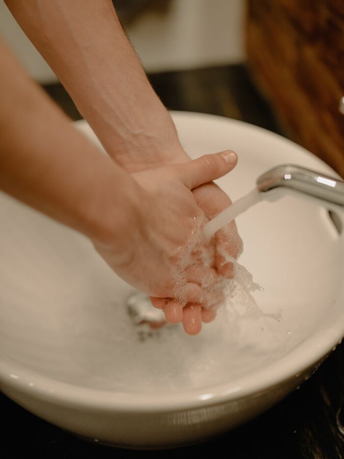 Hands washing in a sink, highlighting hygiene issues that HR might deal with in the workplace.