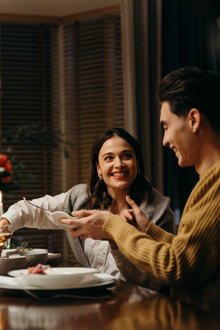 Happy couple sharing food at a dinner table, representing good reasons for getting married.
