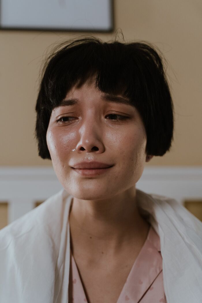 A woman with short dark hair cries, experiencing a deep emotional twist or turn in her life.