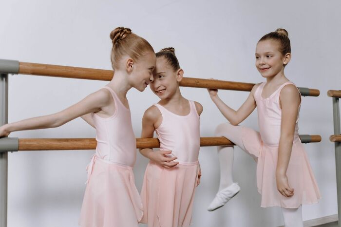 Three young ballerinas smiling at a barre, illustrating the contrast to deeply evil creeps.