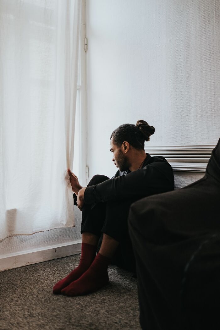 A man sits by a window, looking out with a pensive expression, representing unexpected twists and turns.
