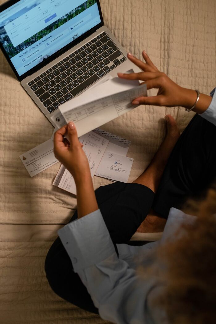 A person sitting with a laptop and papers, revealing behind the scenes secrets companies don't want you to know.