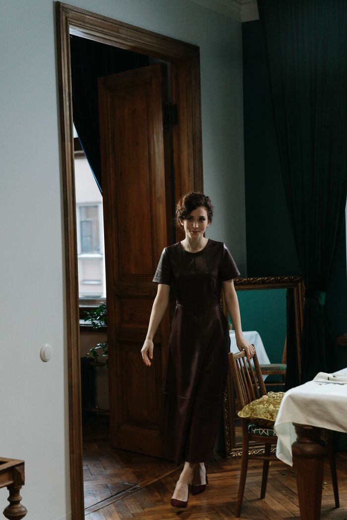 A woman in a dark dress walking into a room, depicting a stereotypically white phrase.
