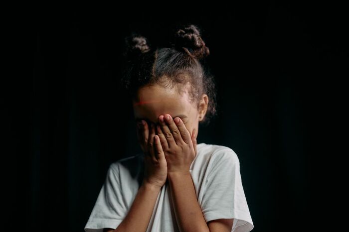 A child covering their face, representing damaging secrets people weren't supposed to know.