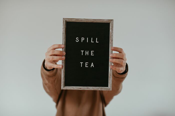 Hands holding a letter board with the popular idiom SPILL THE TEA, representing well-spoken English sayings.