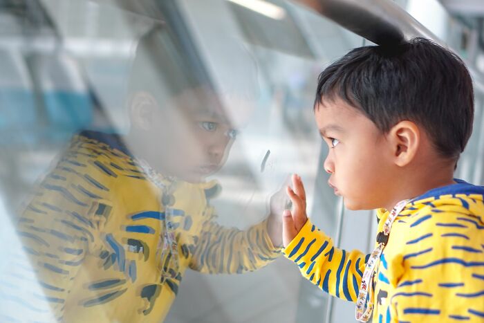 A young child looks intently at their reflection, depicting a moment parents were terrified of their own children.