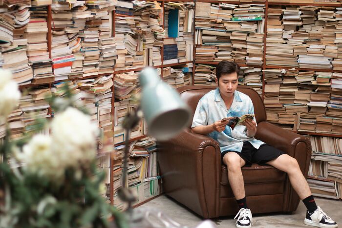 A man takes a Philosophy & Culture Quiz while sitting in a brown armchair surrounded by stacks of books. A man takes a Philosophy & Culture Quiz while sitting in a brown armchair surrounded by stacks of books.