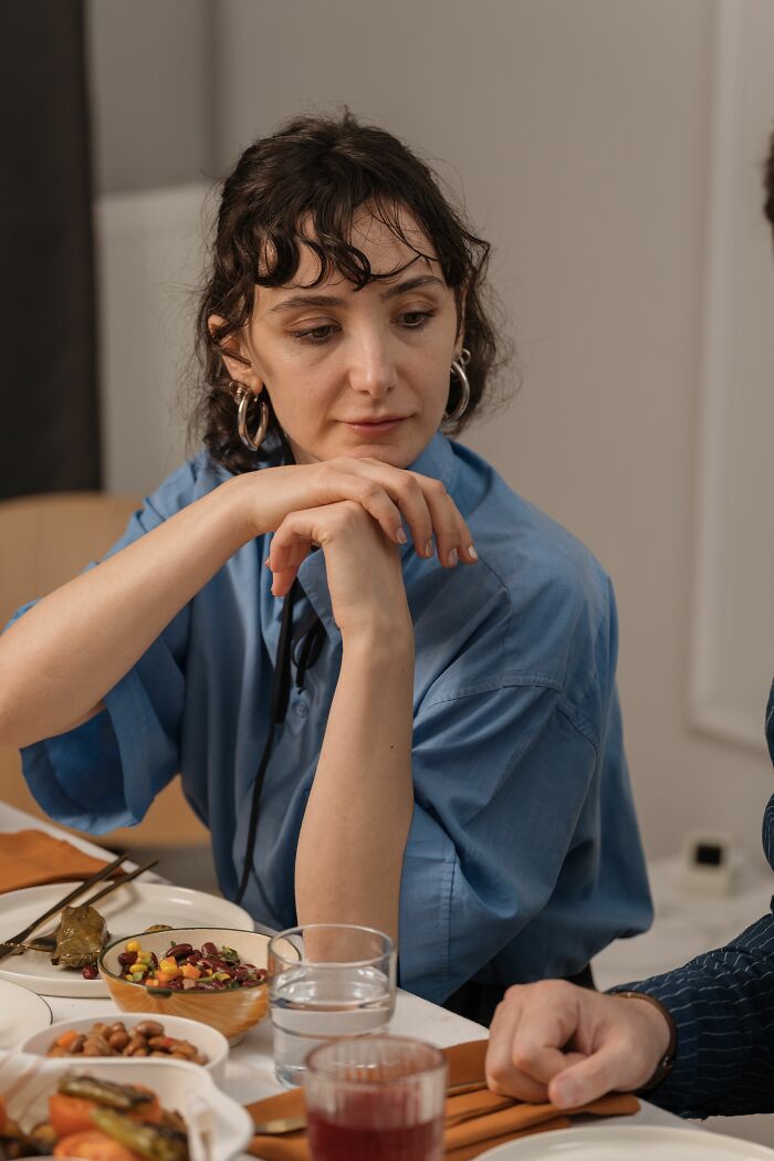 A woman at a dinner table looking thoughtful, considering why women changed their minds about perfect guys.