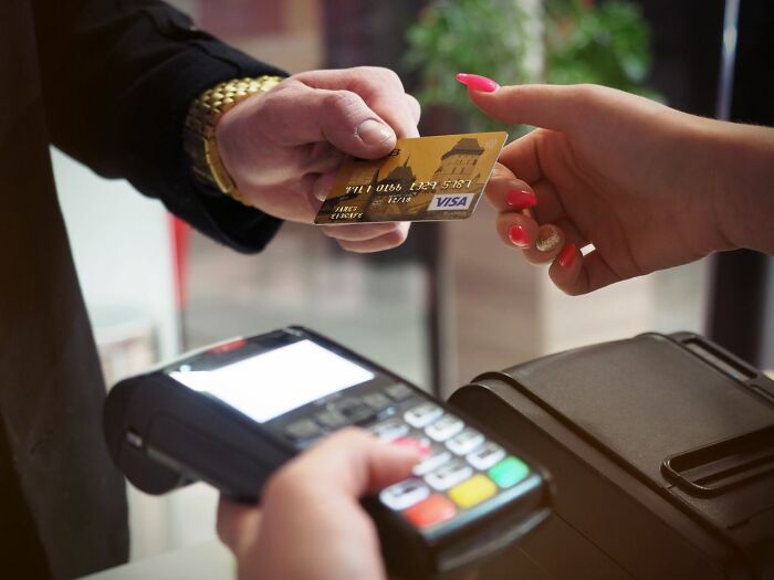 Man paying with a Visa credit card at a point-of-sale terminal, highlighting companies behind the scenes secrets.
