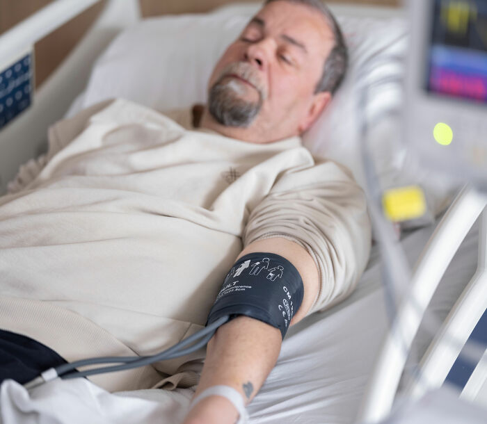 Patient in a hospital bed with a blood pressure cuff, a sign of ongoing monitoring for pneumonia. Patient in a hospital bed with a blood pressure cuff, a sign of ongoing monitoring for pneumonia.