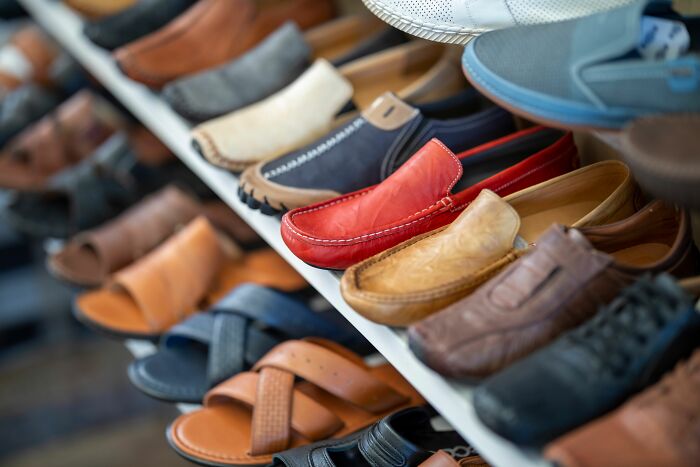 A collection of various men's shoes and sandals displayed on shelves in a store, representing extraordinary history.