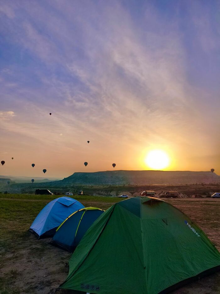 Camping tents and hot air balloons at sunrise, evoking a feeling of deeply evil atmosphere.