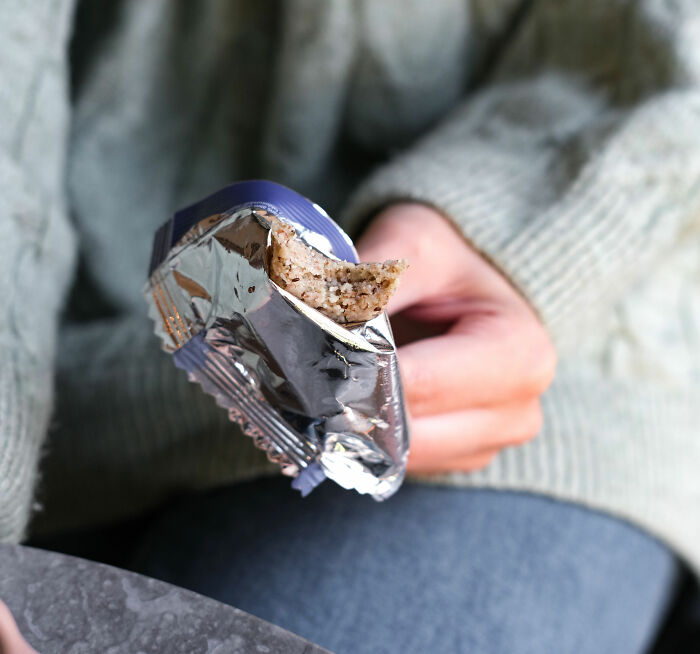 Close-up of person holding a trendy snack food bar partially unwrapped