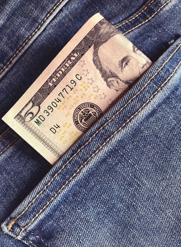 A five-dollar bill peeking out of a jeans pocket, representing a small win among the rarest things.