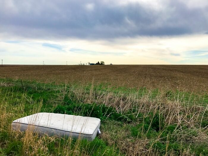 An abandoned mattress in a field with a cloudy sky, representing the shocking and unusual ways people have lost their lives.