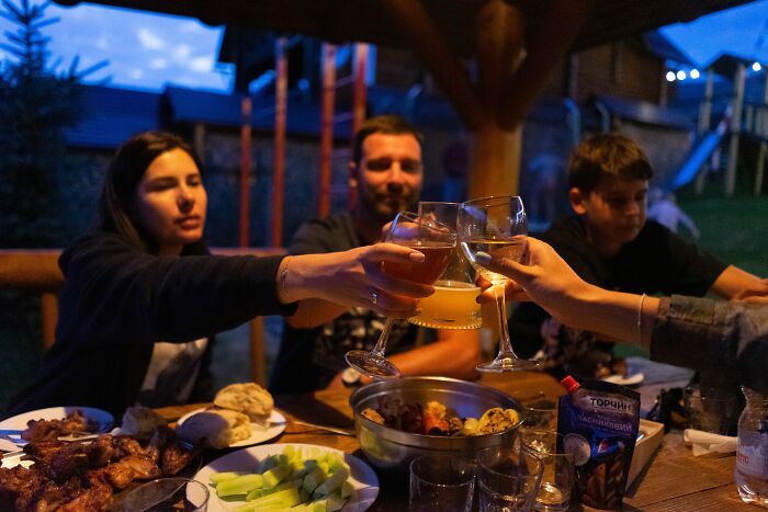 A family enjoying an outdoor dinner, clinking glasses, celebrating their unique version of normal at home.