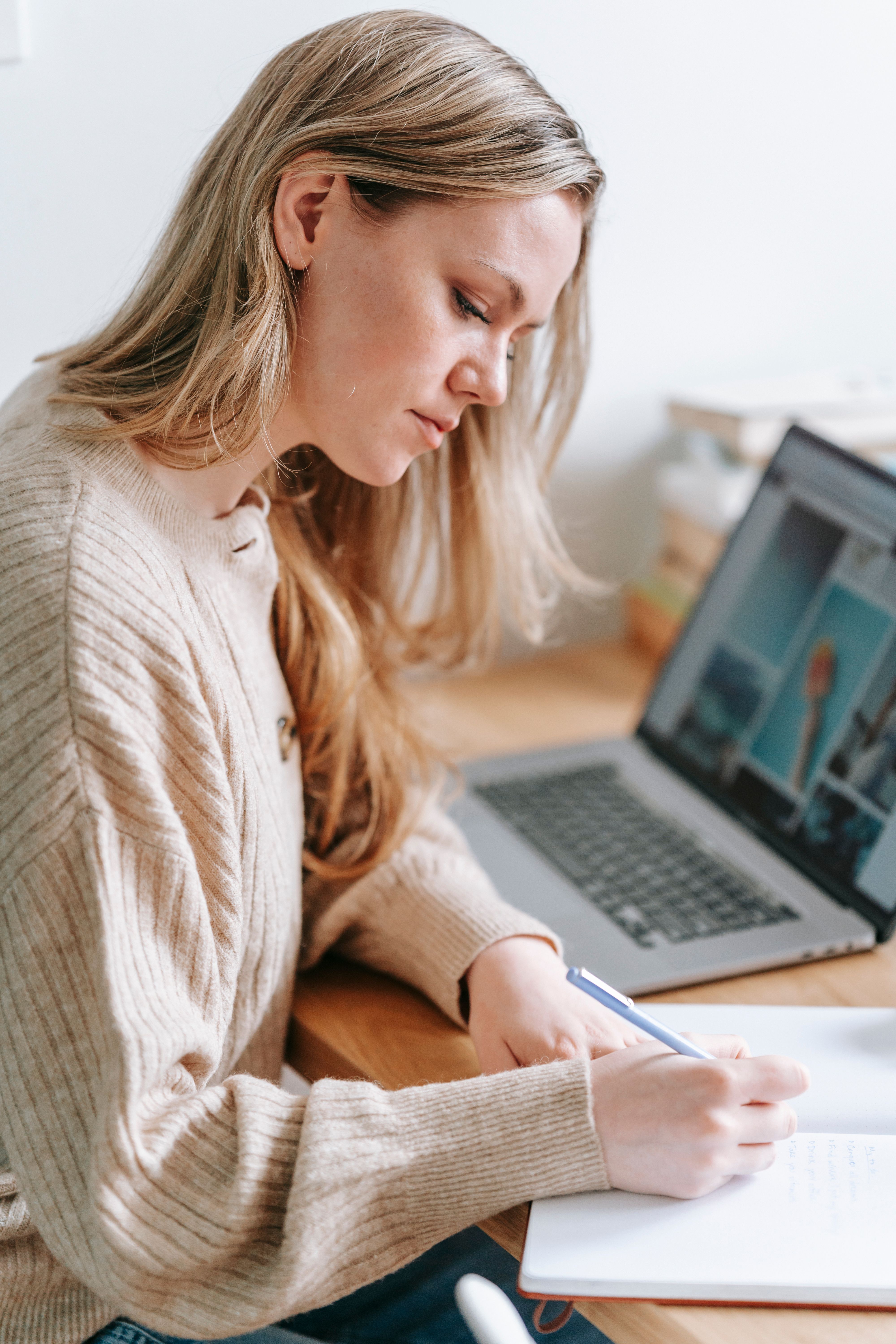 A woman working on a laptop, writing notes in a notebook, highlighting her scary fixation on a groom.