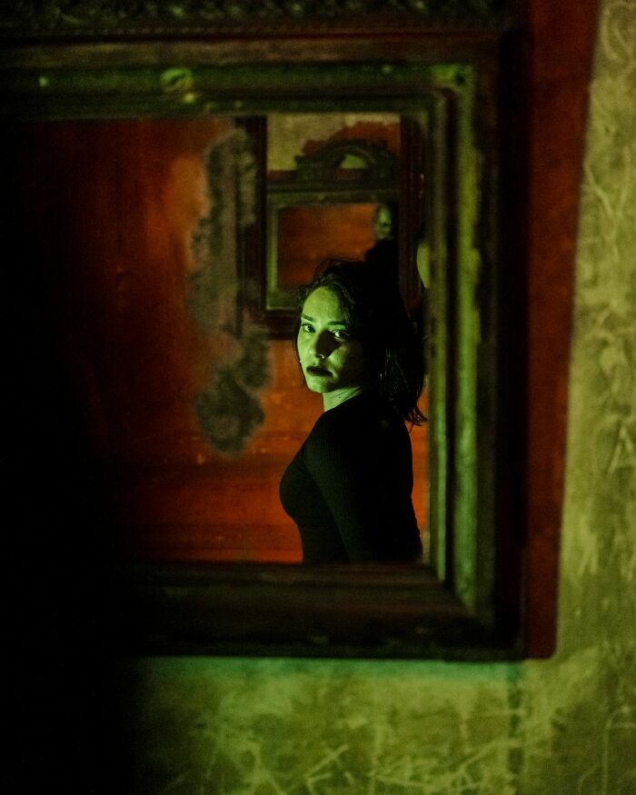 A woman with red lipstick, looking deeply evil, reflected in a mirror, representing people's instincts to avoid creeps.