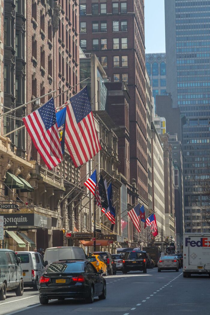 American flags hanging outside buildings on a busy street, representing American habits.