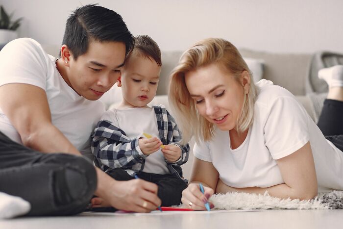 A happy family drawing together on the floor, seemingly free of any psychological red flags.