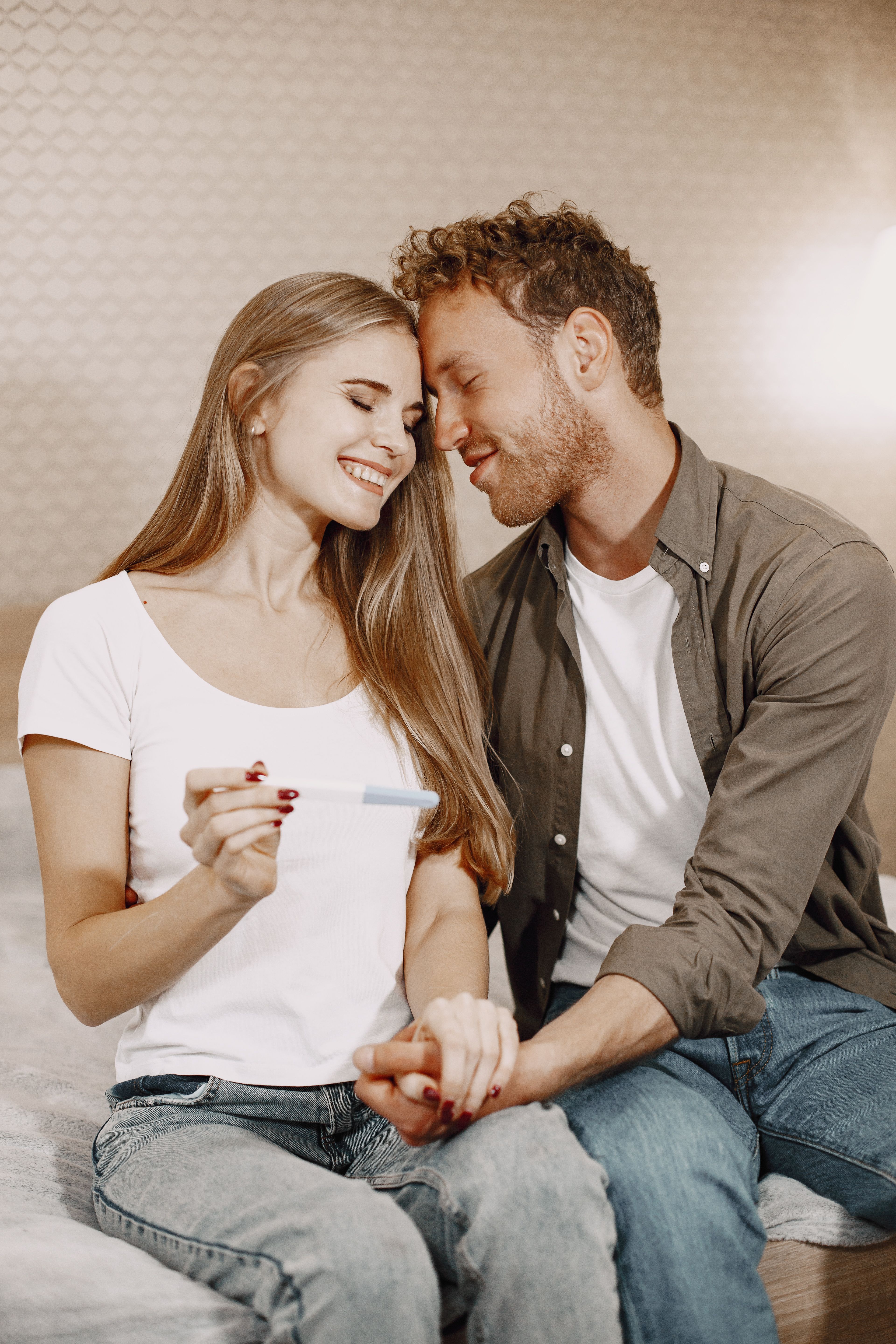 Happy couple, a woman and her groom, holding a positive pregnancy test, showing their scary fixation turning joyful.