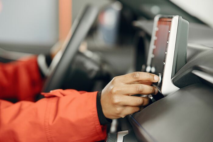 A hand in a red jacket adjusting the car radio, a small cheating red flag in relationships.