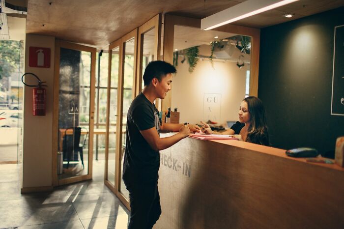 Man talking to a woman at a reception desk, revealing behind the scenes secrets companies dont want you to know.