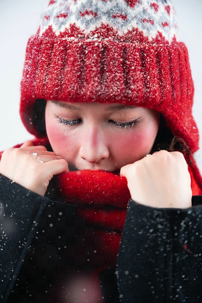 A person in a red winter hat and scarf, with snow on their face, looking cold. This image illustrates shocking ways people have lost their lives.