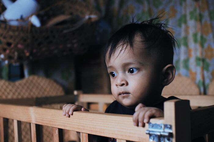 A young child in a crib with a worried expression, illustrating times parents were terrified of their own children.