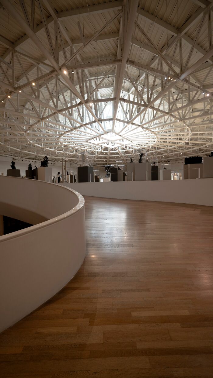 A bright, modern interior with a high, white, geometric ceiling and a curving ramp, not related to office stories.
