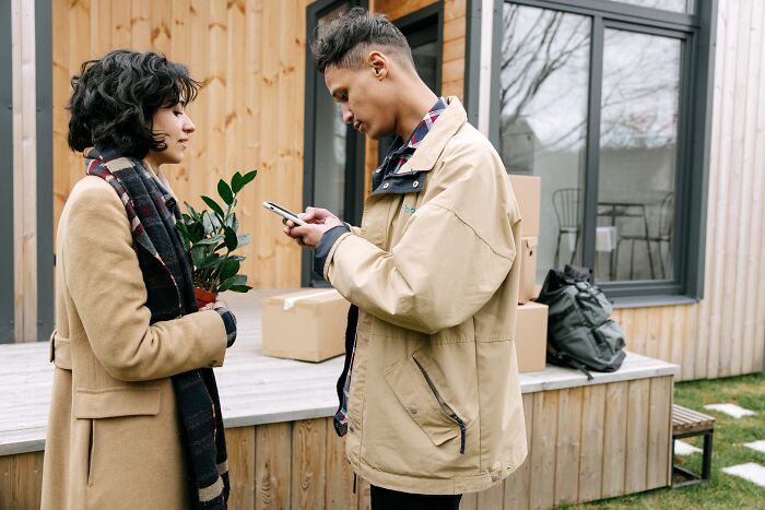 A man looking at his phone while a woman holds a plant, highlighting potential psychological red flags.