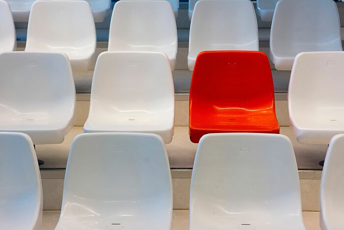 A single red chair stands out among rows of white chairs, representing an odd-one-out general knowledge challenge. A single red chair stands out among rows of white chairs, representing an odd-one-out general knowledge challenge.