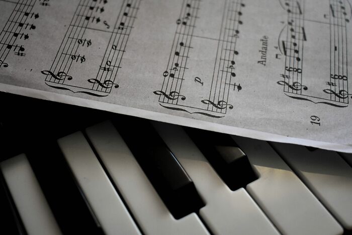 Close-up of classical music sheet resting on piano keys, ideal for a classical music quiz.