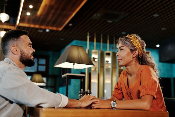 Couple getting married, holding hands and having a serious conversation at a restaurant.