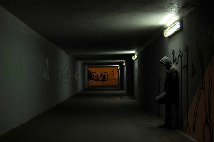Hooded figure in a dark tunnel, creating an uneasy feeling about deeply evil creeps.