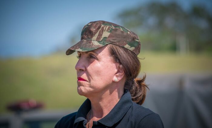 A woman in a camouflage hat, showing a rare moment of focus or contemplation.