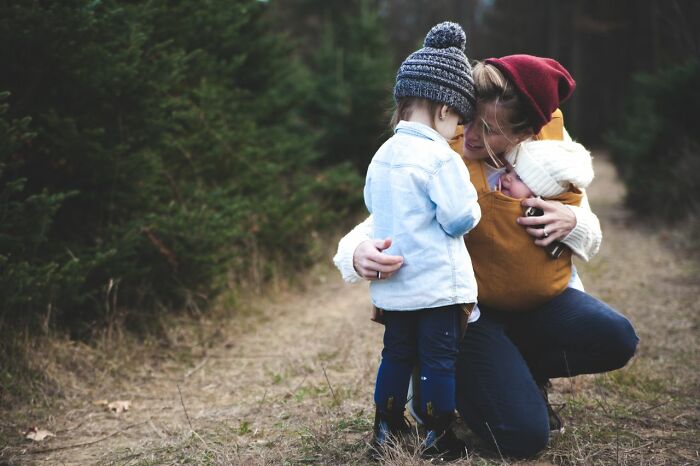 A mother embracing her children in a forest, contrasting with stories of deeply evil people.