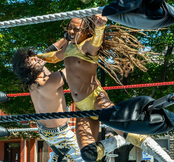 A kids wrestling match, showing one kid delivering a punch to another in a wrestling ring.
