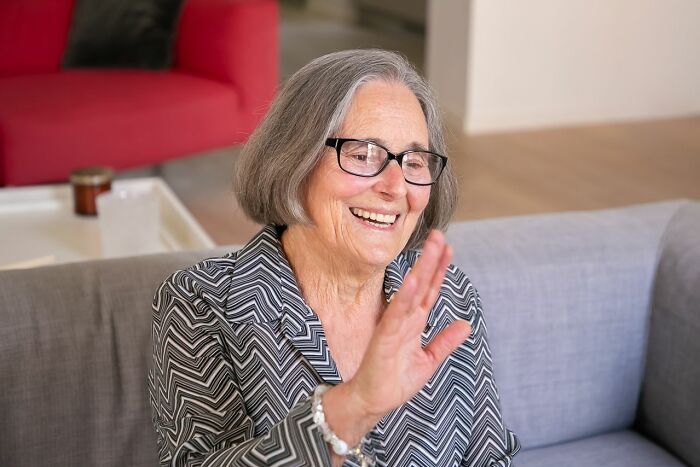 A smiling elderly woman waving, representing people sharing the rarest things that have ever happened.