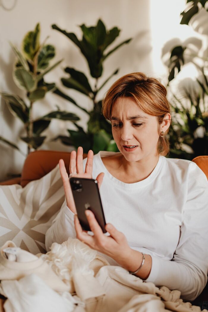 A woman looking frustrated while holding a phone, possibly dealing with entitled friends.
