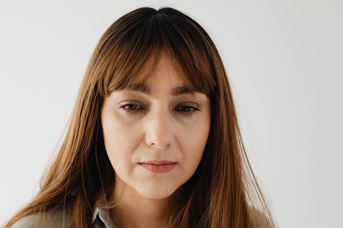A woman with long brown hair looks down, possibly reflecting on life's unexpected twists and turns.