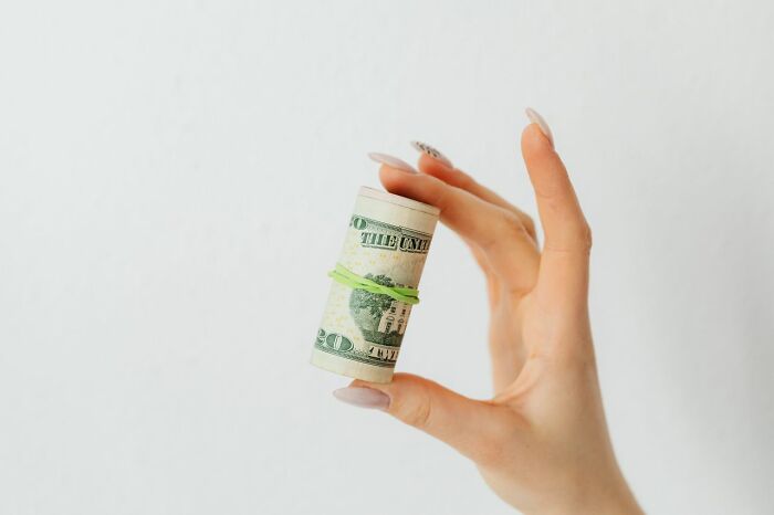 A hand holds a roll of money, a symbol relating to stereotypically white phrases that crack people up.
