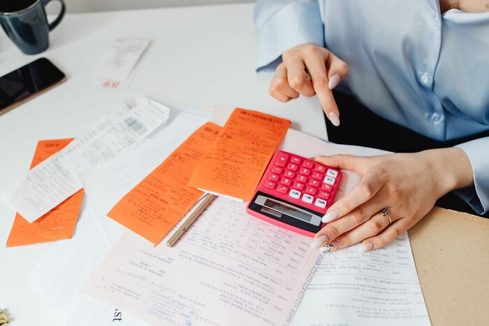 A person calculating finances with receipts, possibly revealing secrets people weren’t supposed to know.
