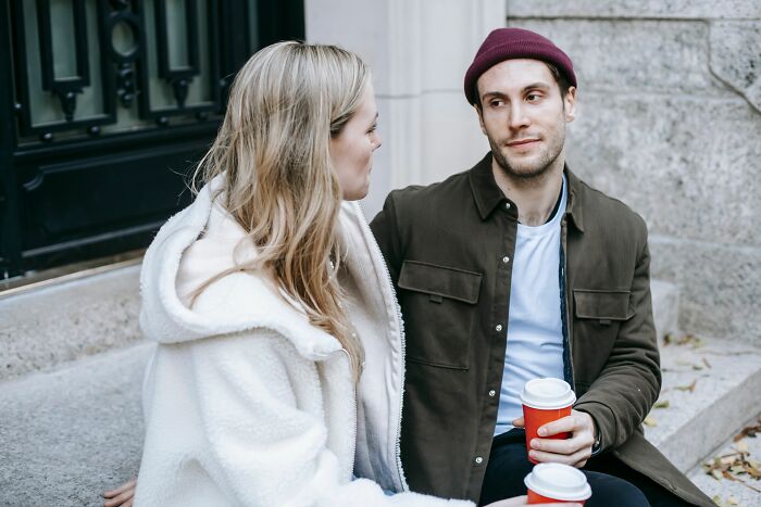 A couple talks outdoors with coffee, perhaps discussing women changing their minds about perfect guys.