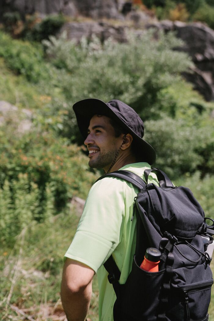 A man with a backpack and hat, smiling outdoors, representing individual growth before getting married.