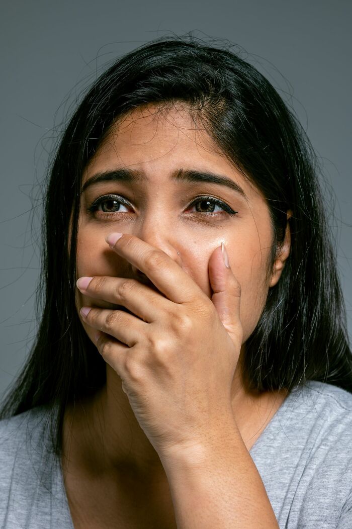 A crying woman with her hand over her mouth, showing the emotional impact of HR dealing with ridiculous problems.
